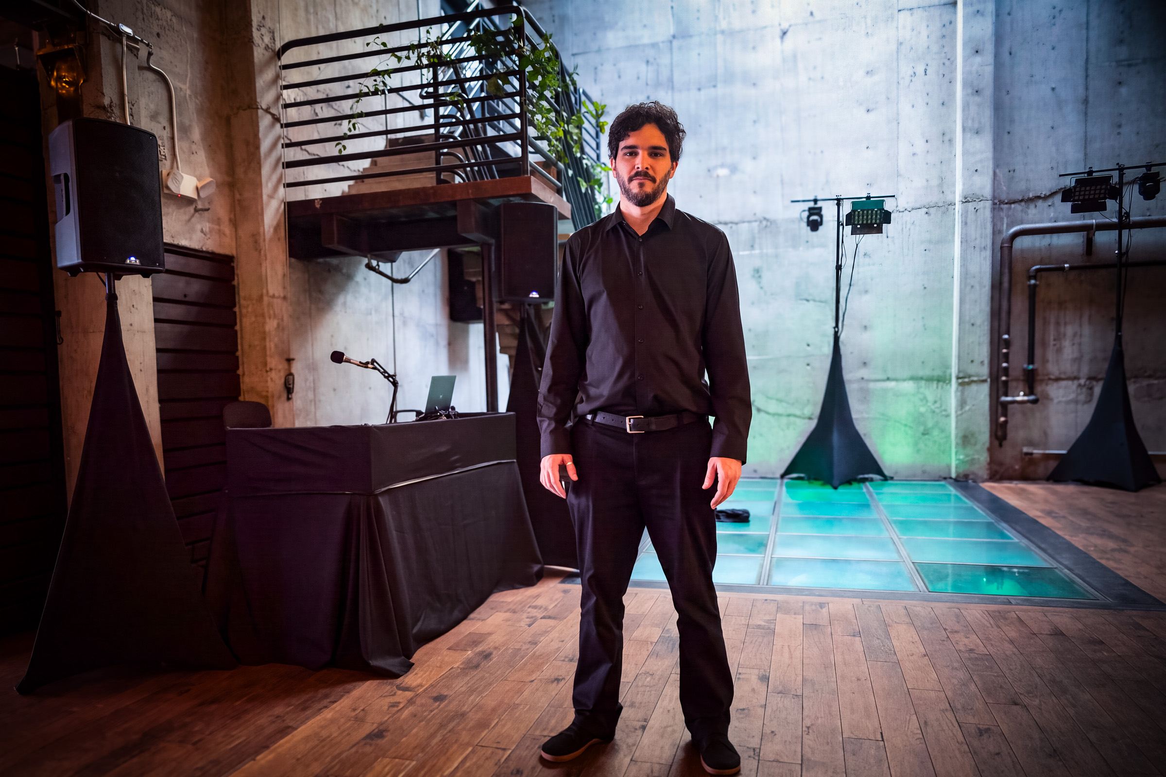 Jacob Black of Black Magic DJ standing in a venue in front of his setup and a lit dance floor